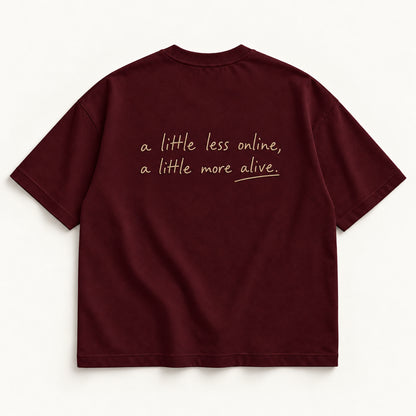 Weinrotes More Alive Tee, Rückseite mit fein gesticktem Schriftzug „a little less online, a little more alive.“