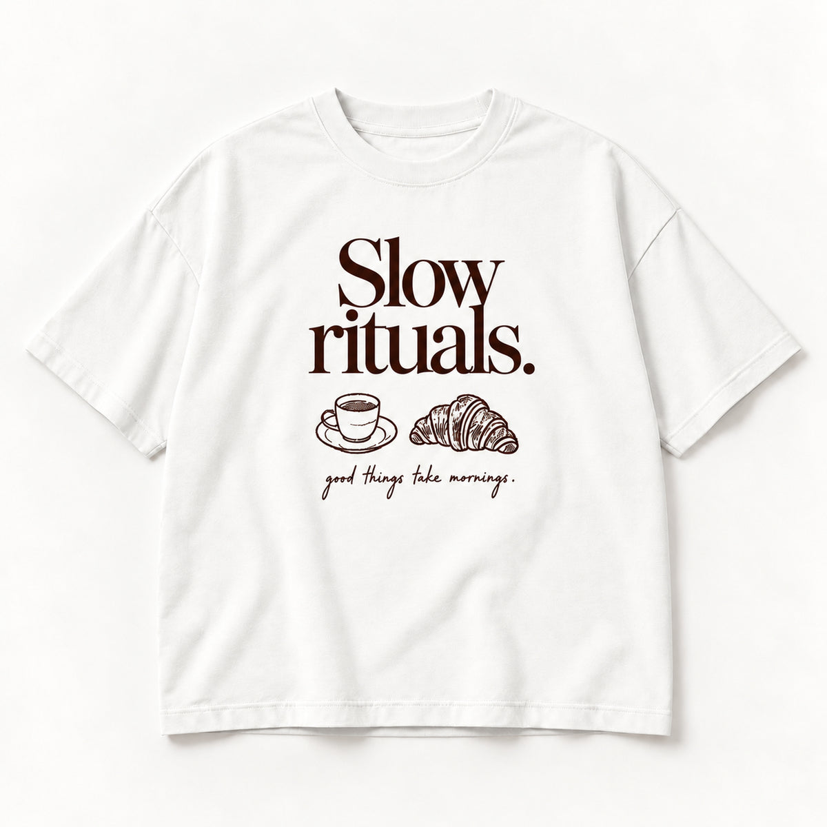 Weißes Slow Rituals Tee, Vorderseite mit dunkelbraunem Schriftzug, Tasse und Croissant