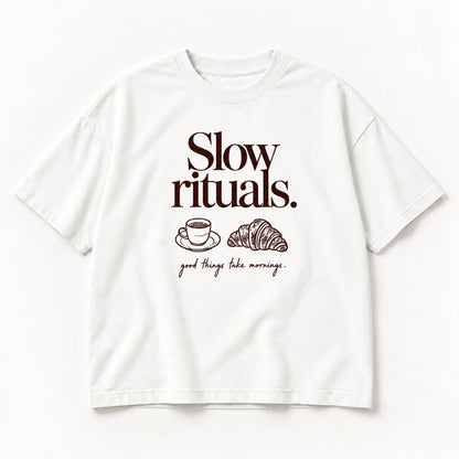 Weißes Slow Rituals Tee, Vorderseite mit dunkelbraunem Schriftzug, Tasse und Croissant