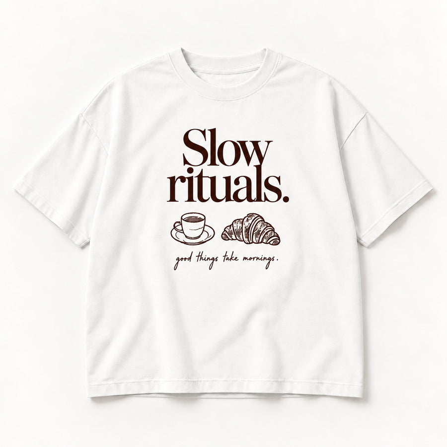 Weißes Slow Rituals Tee, Vorderseite mit dunkelbraunem Schriftzug, Tasse und Croissant