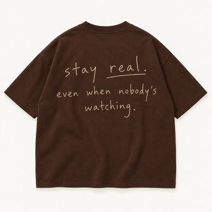 Schokobraunes Stay Real Tee, Rücken mit sandfarbenem Stick „stay real. even when nobody’s watching.“