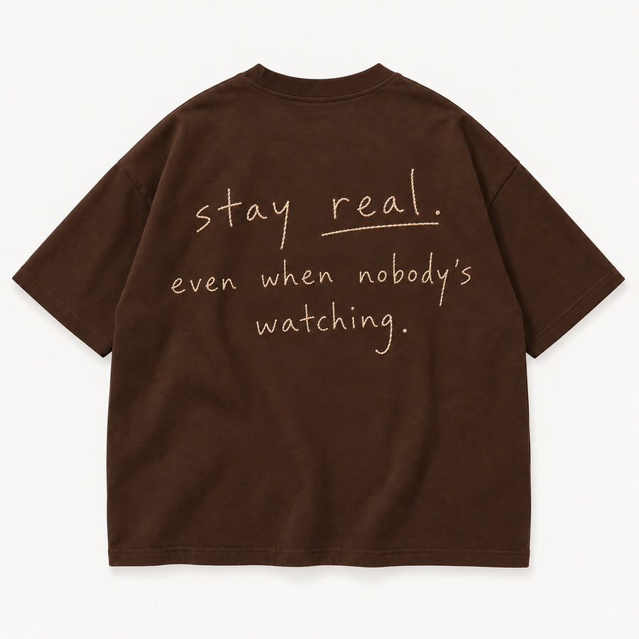 Schokobraunes Stay Real Tee, Rücken mit sandfarbenem Stick „stay real. even when nobody’s watching.“