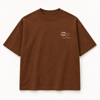 Karamellbraunes Scenic Route Tee von vorn mit hellem JURONOID-Stick, Weglinie und „South Germany“