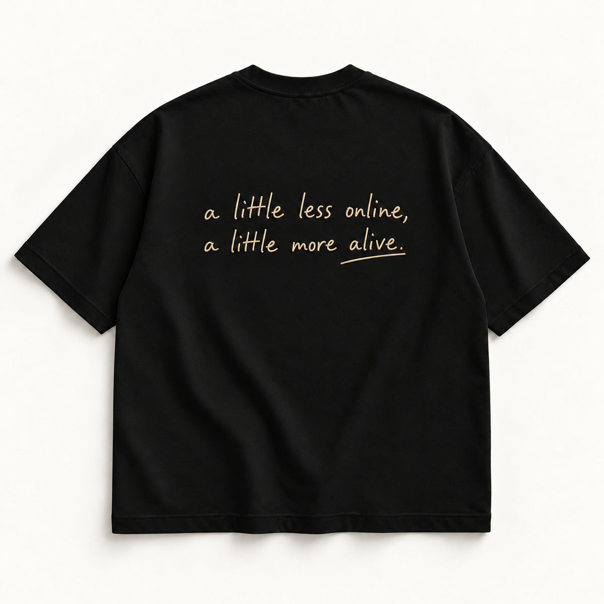 Schwarzes More Alive Tee, Rücken mit champagnerfarbener Handschrift „a little less online, a little more alive.“