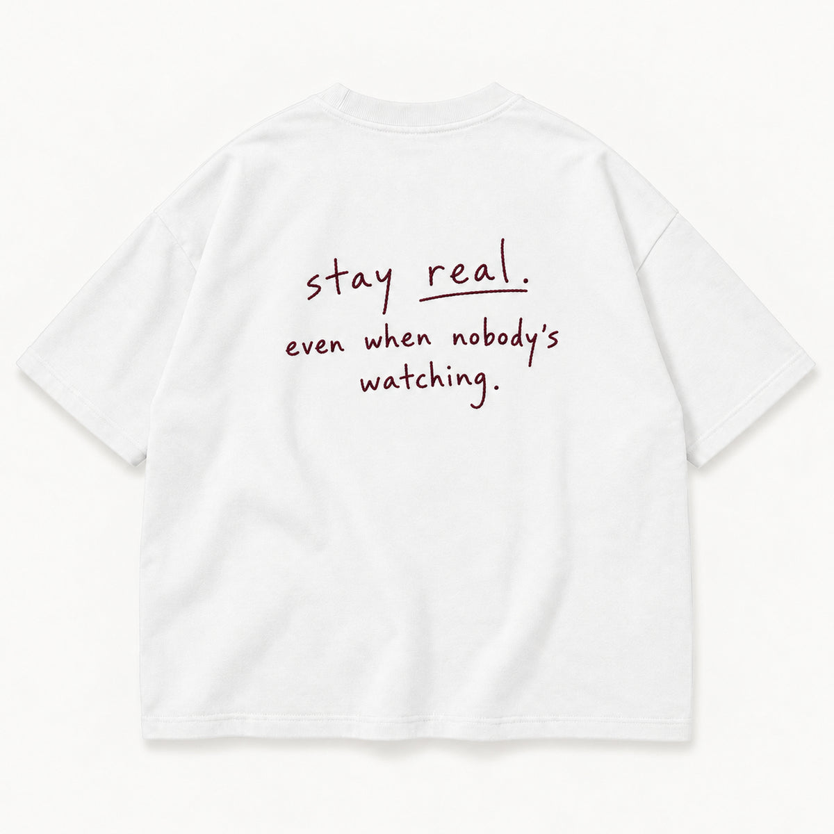 Weißes Stay Real Tee, Rücken mit „stay real. even when nobody’s watching.“ in feinem Merlot-Stick